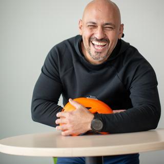 A man laughing with his eyes closed holding a helmet