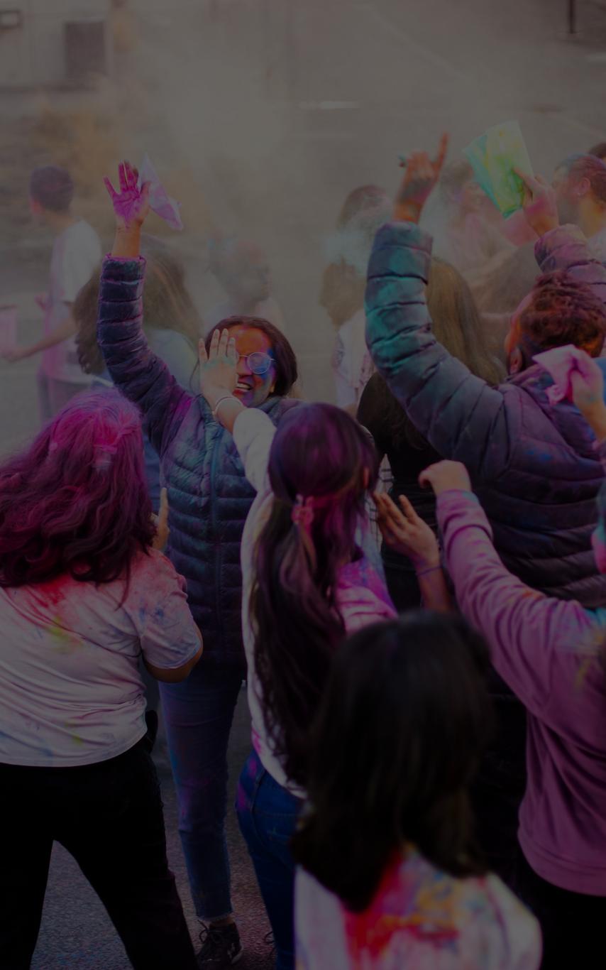 A group of student throwing coloured chalk, celebrating Holi Festival. 